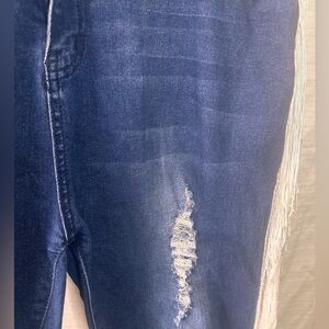 Distressed stretch denim jeans with fringe.